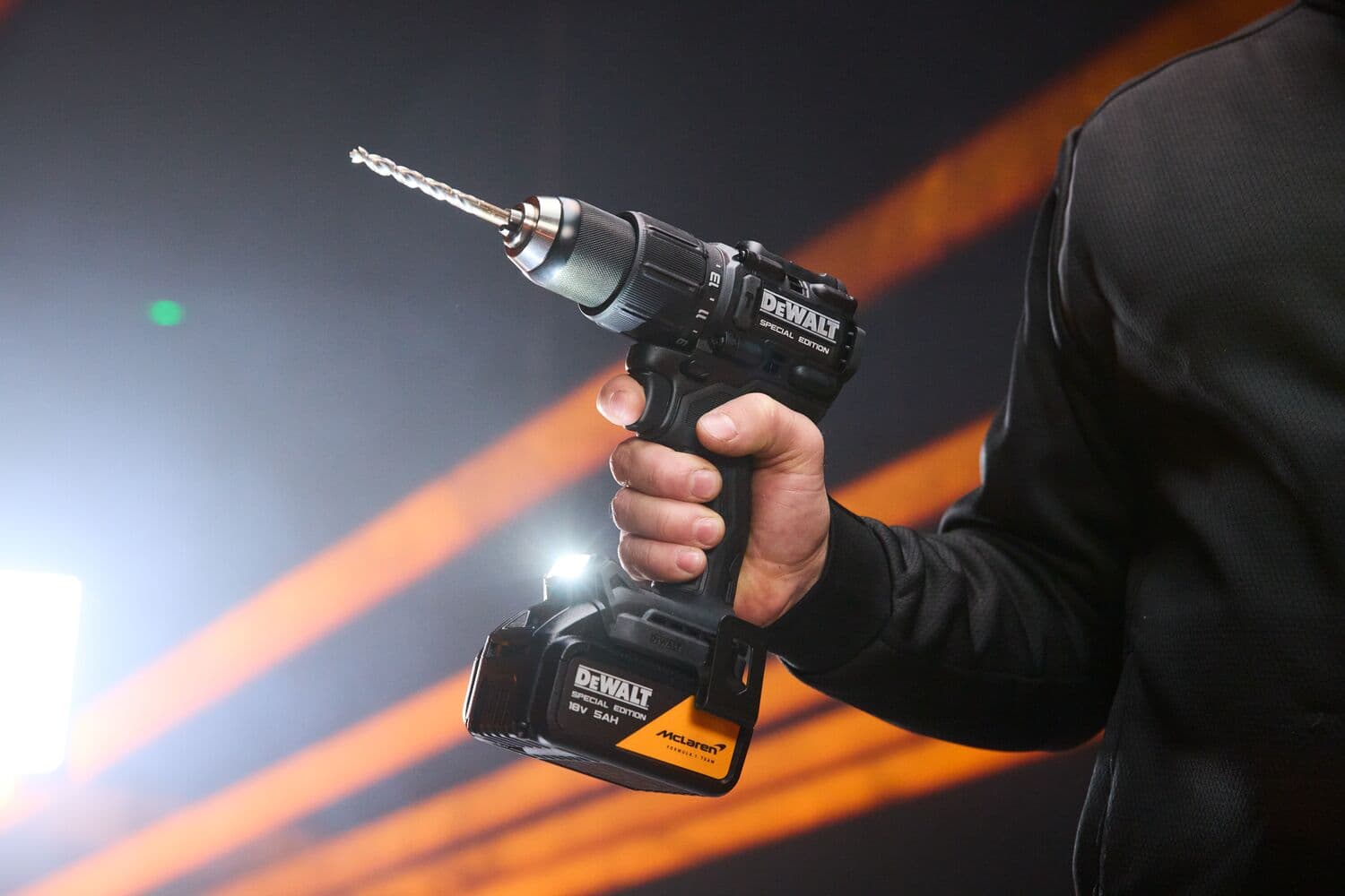 A hand holds the DEWALT x McLaren F1 Team 18V XR Special Edition Hammer Drill Driver with 5Ah battery